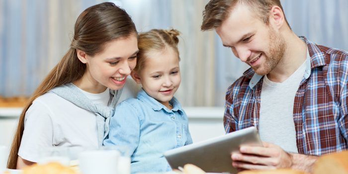 pais com criança, olhando para um tablet